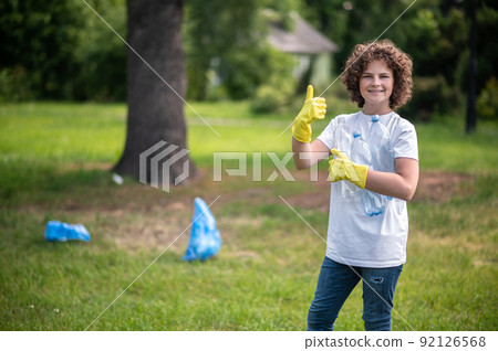 Smiling kid showing thumb up and looking contented 92126568