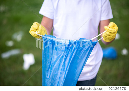 Close up of a kid holding a plastic bag for garbage Close up of a kid holding a plastic bag for garbage 92126578