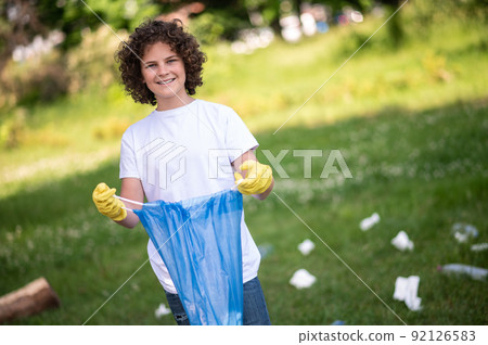 Cute kid holding a bag with garbage and smiling 92126583
