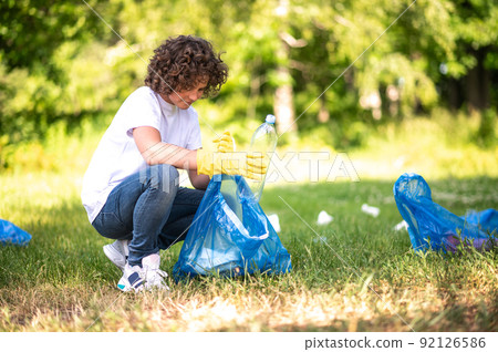 Young guy collecting and sorting garbage in the park Young guy collecting and sorting garbage in the park 92126586