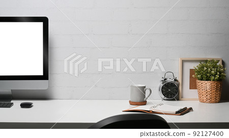 Comfortable home office desk with computer pc, coffee cup, picture frame an houseplant 92127400