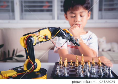 Asian little boy thinking and wait robot arm playing chess Asian little boy thinking and wait robot arm playing chess 92128025