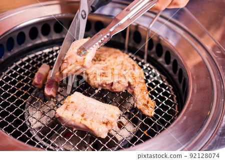 Grilling meat pork Korean BBQ traditional style on stove serve in restaurant Grilling meat pork Korean BBQ traditional style on stove serve in restaurant 92128074