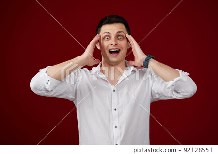 surprised young brunette man in white shirt 92128551