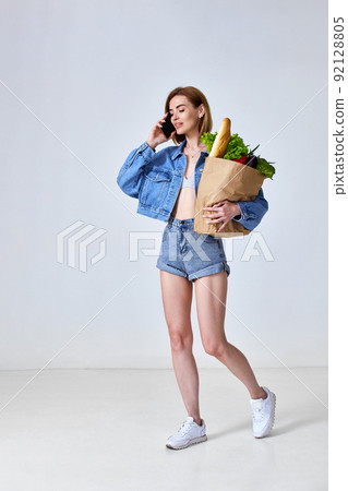 woman holding paper bag with vegetables and smartphone woman holding paper bag with vegetables and smartphone 92128805