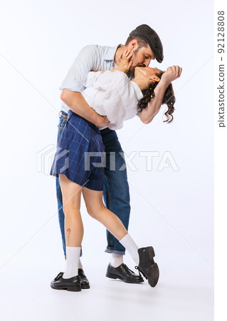 Portrait of young beautiful couple, man and woman, in retro putfit kissing isolated over white studio background 92128808