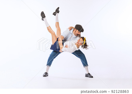 Portrait of young cheerful couple, man and woman in stylish casual outfit dancing isolated over white studio background 92128863