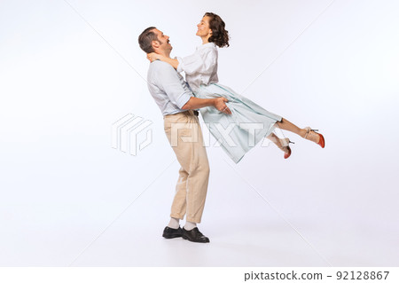 Portrait of young beautiful couple, man and woman, dancing isolated over white studio background. Vintage lifestyle 92128867
