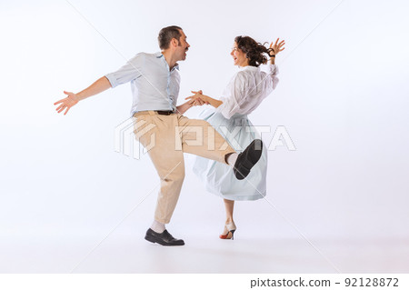 Portrait of young stylish couple, man and woman, dancing isolated over white studio background. Classic dance styles 92128872