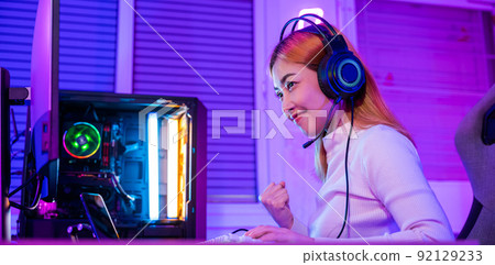 Asian gamer playing online video game excited on desktop computer Asian gamer playing online video game excited on desktop computer 92129233