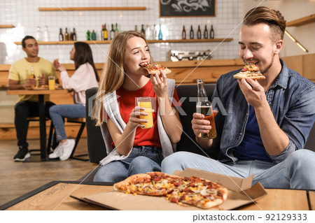 Young couple eating delicious pizza in cafe Young couple eating delicious pizza in cafe 92129333