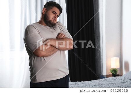 Overweight man suffering from depression at home Overweight man suffering from depression at home 92129916