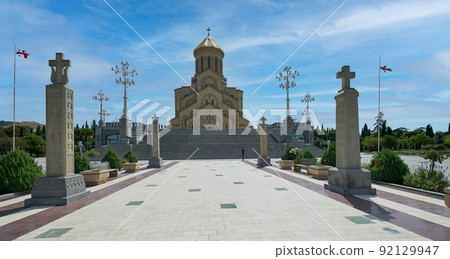 Holy Trinity Cathedral of Tbilisi , Georgia external daylight view showing unique architecture of the cathedral with people walking on the stairs and clouds in the sky Holy Trinity Cathedral of Tbilisi , Georgia external daylight view showing unique architecture of the cathedral with people walking on the stairs and clouds in the sky 92129947