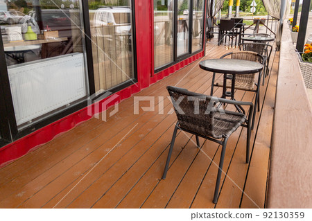 row of wicker chairs and glass tables near windows of roadside cafe, empty row of wicker chairs and glass tables near windows of roadside cafe, empty 92130359