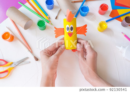 Holiday easy DIY craft idea for kids. Toilet paper roll tube toy chick baby on a white background with colored paper.. Creative Easter decoration eco-friendly, reuse, recycle, zero waste handmade 92130541