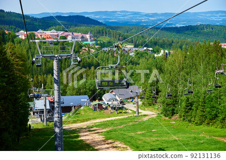 Beautiful mountains, covered with forest and open cable car line. Karpacz resort in Poland with lift road. Family outdoor recreation in mountains Beautiful mountains, covered with forest and open cable car line. Karpacz resort in Poland with lift road. Family outdoor recreation in mountains 92131136