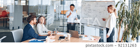 Asian man and woman conducts a meeting for employees near a flipchart and explains the work strategy 92131263