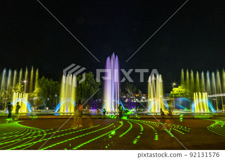 The fountain is dancing to light music and colorful lighting. Green laser light adds illumination The fountain is dancing to light music and colorful lighting. Green laser light adds illumination 92131576