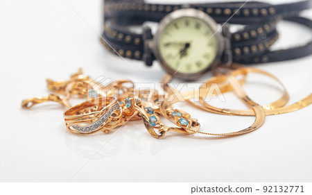 Women's wristwatch with leather strap lies next to the gold chain and necklace with precious stones 92132771