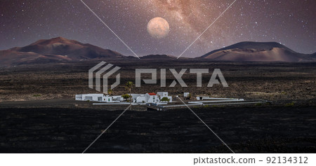 Amazing nocturnal panoramic landscape of volcano craters in Timanfaya national park. Full moon over La Gueria, Lanzarote island, Canary islans, Spain. Artistic night sky picture 92134312