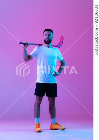 One sportive man, floorball player with floorball stick training isolated on lilac color background in neon. Sport, action and motion, movement, healthy lifestyle One sportive man, floorball player with floorball stick training isolated on lilac color background in neon. Sport, action and motion, movement, healthy lifestyle 92136633
