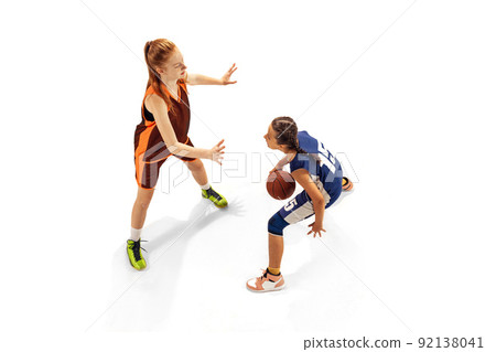 Play defense. Two basketball players, young girls, teen training with basketball ball isolated on white background. Concept of sport, team, enegry, competition, skills Play defense. Two basketball players, young girls, teen training with basketball ball isolated on white background. Concept of sport, team, enegry, competition, skills 92138041