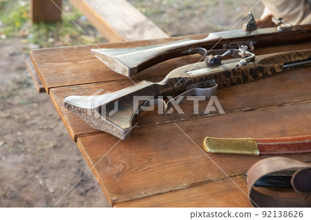 old shotgun with a wooden barrel and an iron stock close-up 92138626