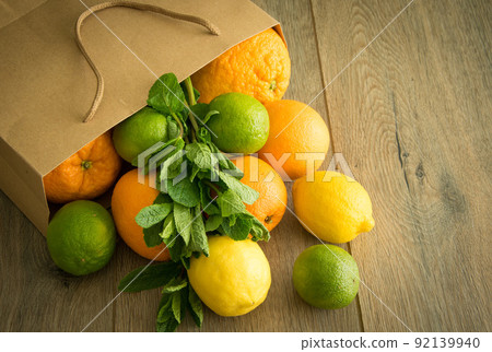 Paper bag with fresh citrus fruits, mint bunch brown wooden background 92139940