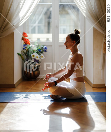 Young fitness woman doing meditation during morning yoga routine at home Young fitness woman doing meditation during morning yoga routine at home 92140039