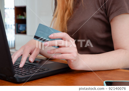 Woman with laptop and credit card at home . Online payment, digital banking. Online shopping concept, young woman hands holding mobile smart phone and credit card with laptop on table. Woman with laptop and credit card at home . Online payment, digital banking. Online shopping concept, young woman hands holding mobile smart phone and credit card with laptop on table. 92140076