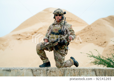Soldier or military man sit with guarded position and look at camera in area look like desert 92141265