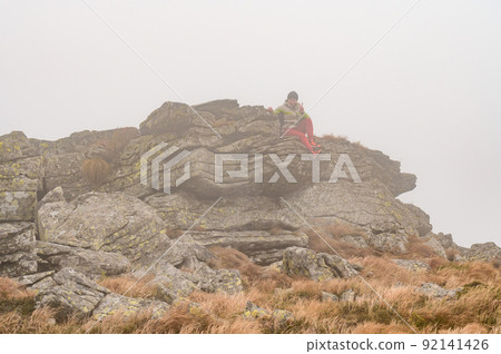 A man with a backpack for a hike climbs to the top of the mountain on a rocky path, a tourist hike in the Carpathians in Ukraine. 92141426