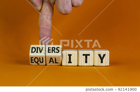 Diversity and equality symbol. Businessman turns wooden cubes, changes the word 'equality' to 'diversity'. Beautiful orange background. Business, diversity and equality concept. Copy space. Diversity and equality symbol. Businessman turns wooden cubes, changes the word 'equality' to 'diversity'. Beautiful orange background. Business, diversity and equality concept. Copy space. 92141900
