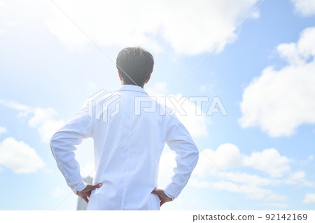 一個身穿白大褂、雙手放在腰間向前看的人的後視圖 92142169