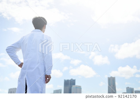 一個身穿白大褂、一隻手放在腰間向前看的男人的後視圖 92142170