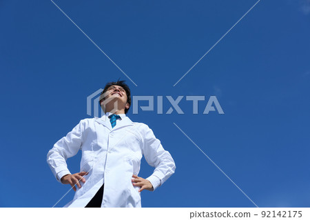 一個身穿白大褂的男人在藍天下雙手叉腰向前看 一個身穿白大褂的男人在藍天下雙手叉腰向前看 92142175