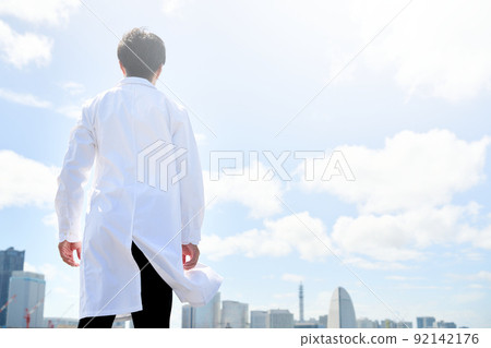 一個穿白大褂的男人盯著遠處的建築小鎮的後視 一個穿白大褂的男人盯著遠處的建築小鎮的後視 92142176