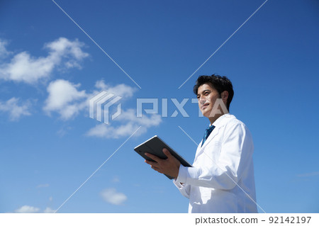 藍天下拿著平板電腦的白人 92142197