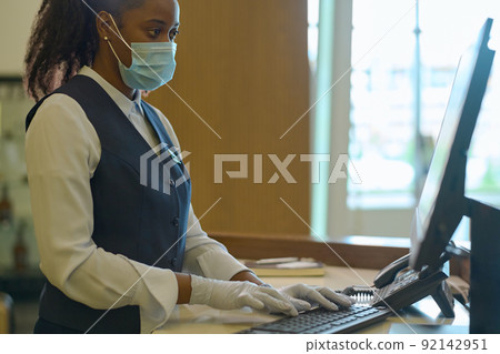 Young female receptionist entering personal data of hotel guests into database 92142951