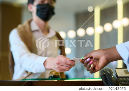 Hand of black woman taking keycard held by male guest over reception counter Hand of black woman taking keycard held by male guest over reception counter 92142953