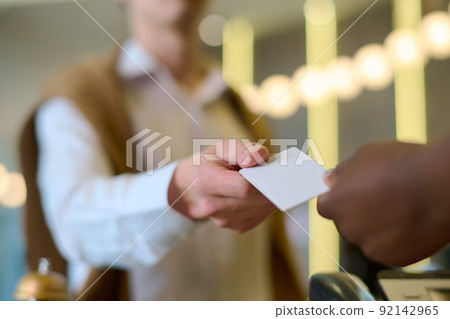 Hand of young male travler or guest of hotel taking keycard on reception Hand of young male travler or guest of hotel taking keycard on reception 92142965