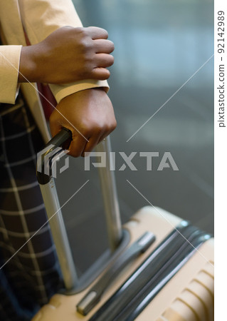 Hands of young elegant black woman holding by handle of suitcase with luggage 92142989