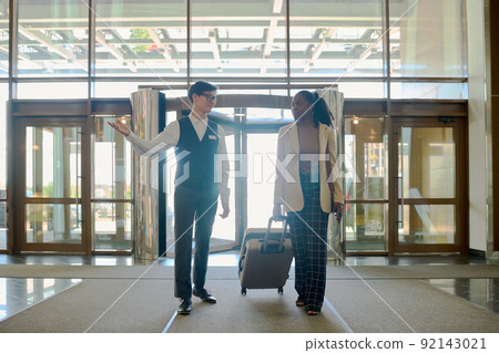 Young elegant owner of luxurious hotel meeting African American traveler Young elegant owner of luxurious hotel meeting African American traveler 92143021