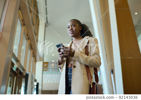 Young businesswoman or female traveler in elegant coat with handbag on shoulder Young businesswoman or female traveler in elegant coat with handbag on shoulder 92143036