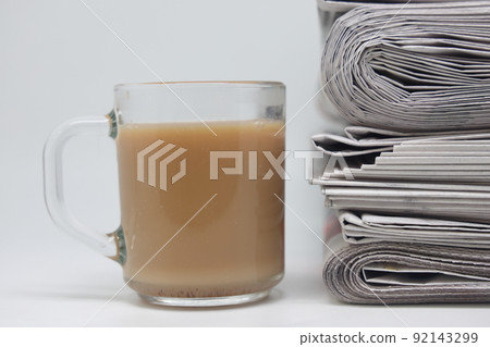 Folded newspapers stacked and a cup of tea with milk, the concept of reading the news in the morning Folded newspapers stacked and a cup of tea with milk, the concept of reading the news in the morning 92143299