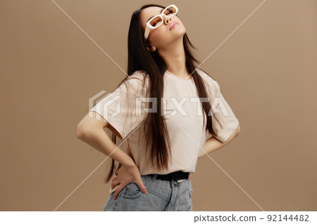young woman in a beige T-shirt with glasses posing clothing fashion beige background young woman in a beige T-shirt with glasses posing clothing fashion beige background 92144482