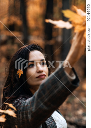Portrait brunette woman with fall yellow leaves in long hair on autumn nature background. Portrait brunette woman with fall yellow leaves in long hair on autumn nature background. 92144960