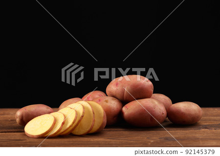 Pile of potatoes lying on wooden boards 92145379