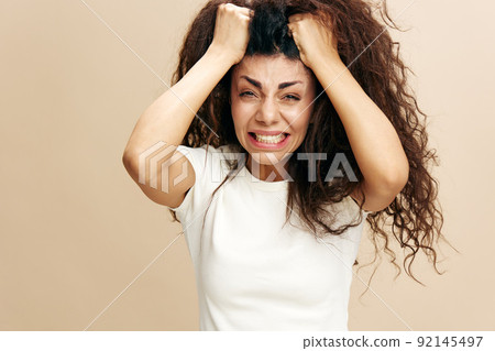 PROBLEMS CONCEPT. Crazy beautiful Latin female with afro rips out hair, have big troubles. Fashion. Studio shoot over pastel beige background. Copy space, free place for design ad PROBLEMS CONCEPT. Crazy beautiful Latin female with afro rips out hair, have big troubles. Fashion. Studio shoot over pastel beige background. Copy space, free place for design ad 92145497