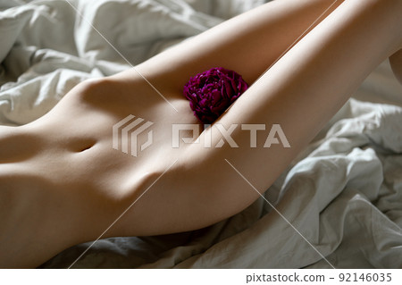 Girl with peonies instead of underwear laying at the bed 92146035